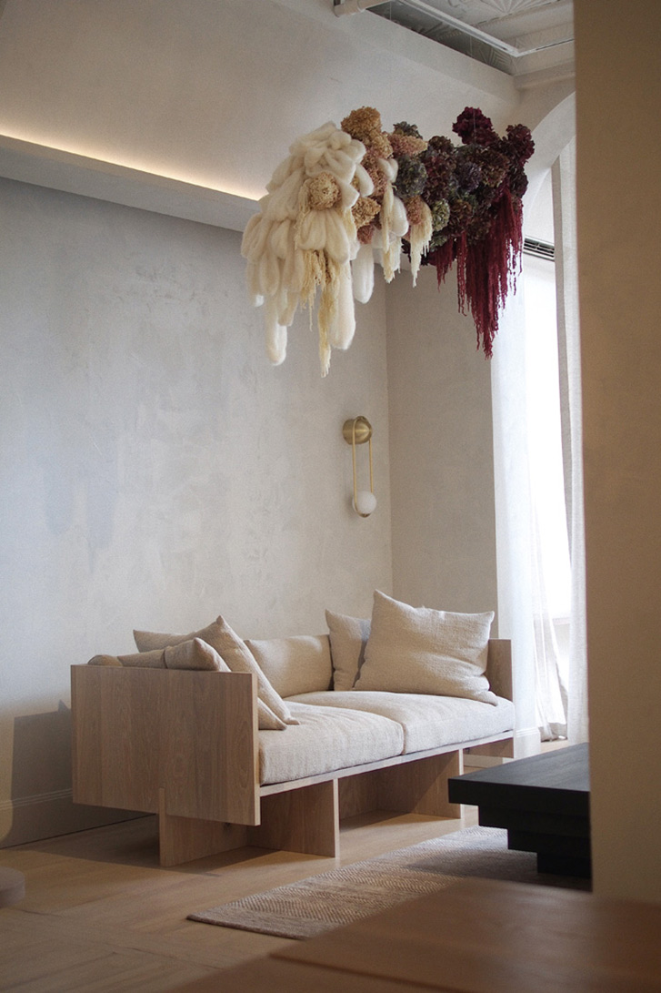A cream coloured daybed sits in a corner with wall hangings above it