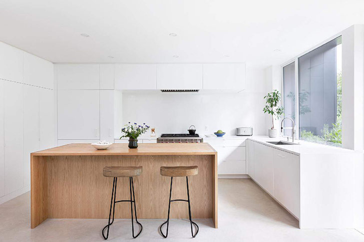 The kitchen is white with a wooden island in the center