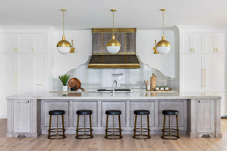 A large kitchen with luxe bronze light fixtures and a grey wood island
