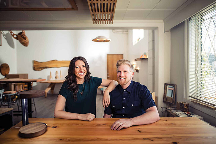 Designers Kaly Ryan and Bram Sawatzky sitting together at a wood table