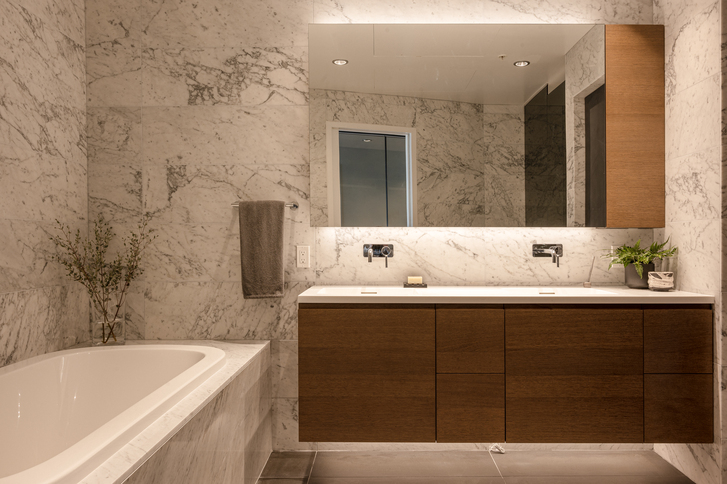 Marble-walled bathroom with sink and bathtub