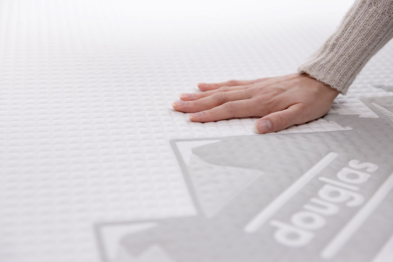 Feeling the surface texture of a cooling mattress made by Douglas.