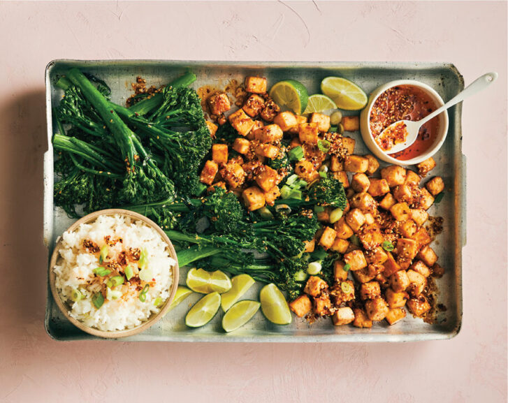 Vegan Firecracker Tofu with Broccolini and Chili Garlic Oil on a rectangular plate on a pink background