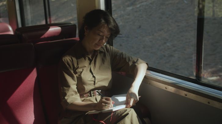 jackie ellis on a train writing in a journal