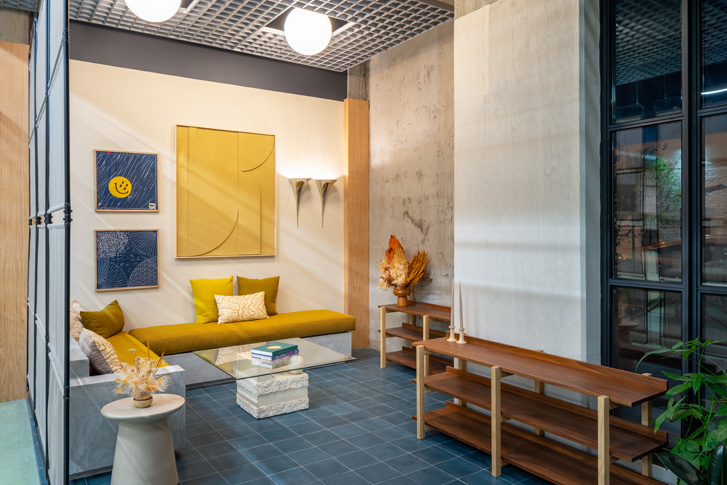 Waiting area with yellow fabric bench, shoe rack and yellow and blue art on walls