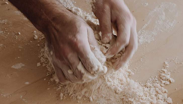 A pair of hands kneading dough for a cooking recipe