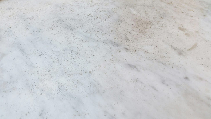 A photo I snapped of one sad restaurant marble tabletop. Thankfully our expert tells us there's a way to avoid this gross, blackhead-like situation. (Photo by Julia Dilworth). 