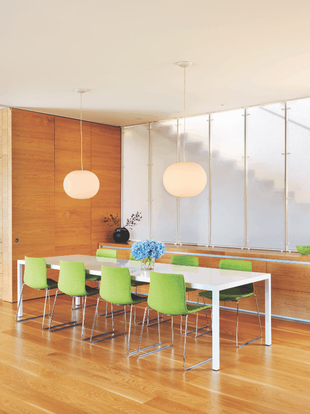 DINING ROOM: The room features a warm embrace of white oak floors and millwork. Light from an upper floor courtyard spills in thanks to a wall of translucent resin panels.