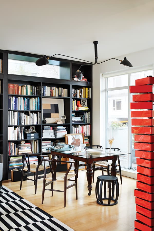 Custom shelving in the dining area provides space for stowing all of Pereira’s books and treasures. “The small space keeps me disciplined,” laughs Pereira. “It would be horrifying how much I could accumulate if I had a larger space.” A red, sculptural Capellini storage unit offers even more hiding places for everyday clutter like bills and mail. “Pretty much everything has to function like that when you live in a home this size.”.
