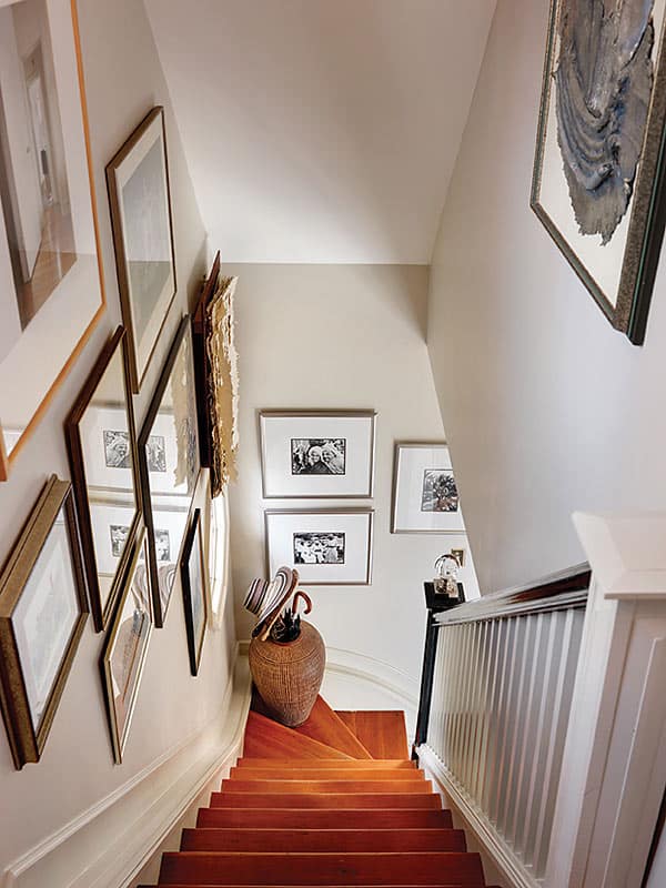 Hall of Fame | Many of the paintings and photos in the stairwell are from the couple’s time in Old Montreal, when Peggy taught at a women’s college. The glass-orb finial on the newel post is another find of designer Coco Cran.