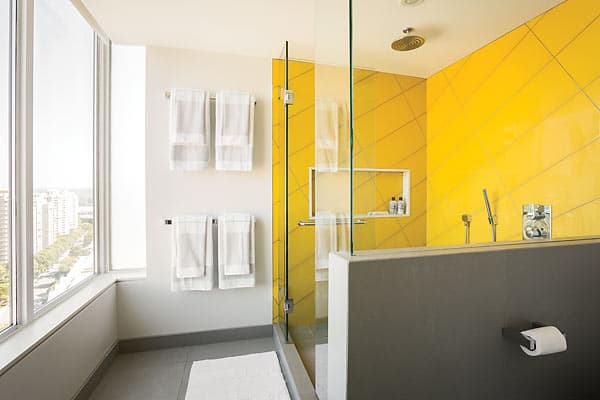 “We wanted to add something sculptural in the powder room without crowding the mirror and interrupting the flush oak mirror frame” says Falkenberg. “Hanging pendants gave these modern details room to breathe while providing even, eye-level lighting.” The yellow tiles in the shower were installed flush to the drywall and at a 30 degree angle for a clean and playful effect. “The yellow is meant to be invigorating in the morning.”