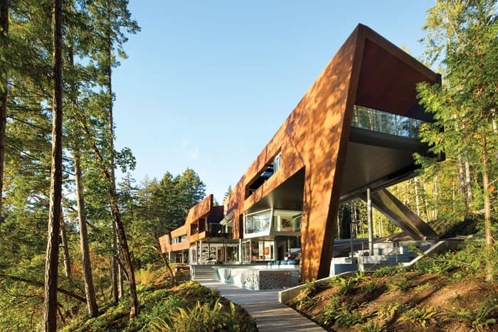 The origami-like shape of this Gulf Islands home hugs the shoreline. It was actually built in a prefab factory, then trucked and barged over to the island, a system that reduces waste and saves energy. The facade is constructed of carefully rusted steel, which architect Tony Robins—ever the perfectionist—sourced to perfectly match the bark of the arbutus trees surrounding the home.