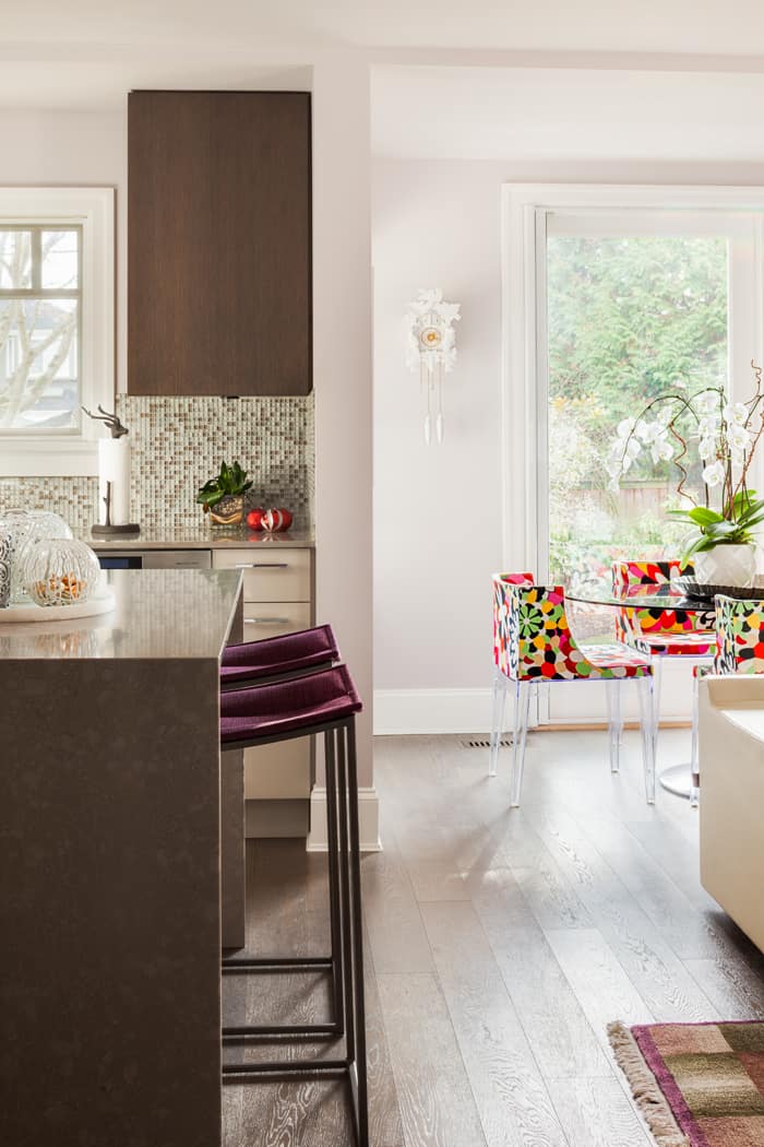 The kitchen's surfaces all tie in to the larger design: dark-stained oak millwork complements the floors and Caesarstone counters add a contemporary note. Mademoiselle chairs by Kartell create a colourful, inviting breakfast nook.