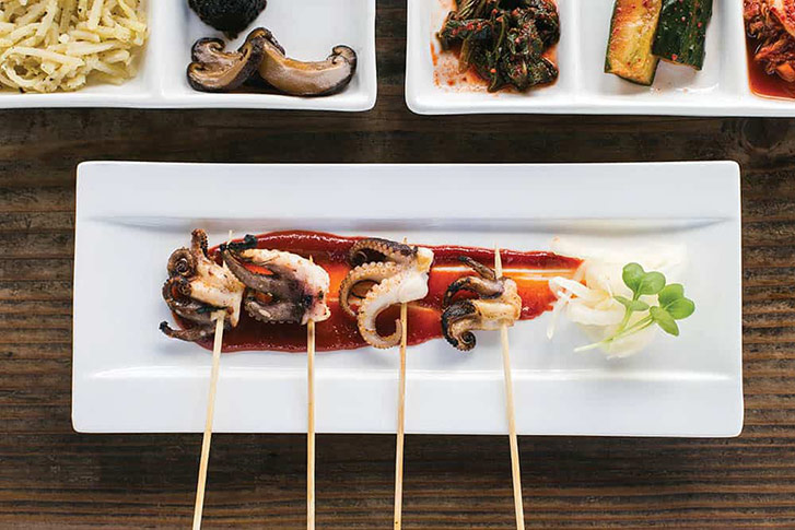 Octopus skewers, (pickles and kimchi, and rice are served at FuseBOX. (Photo: Jen Fedrizzi.)