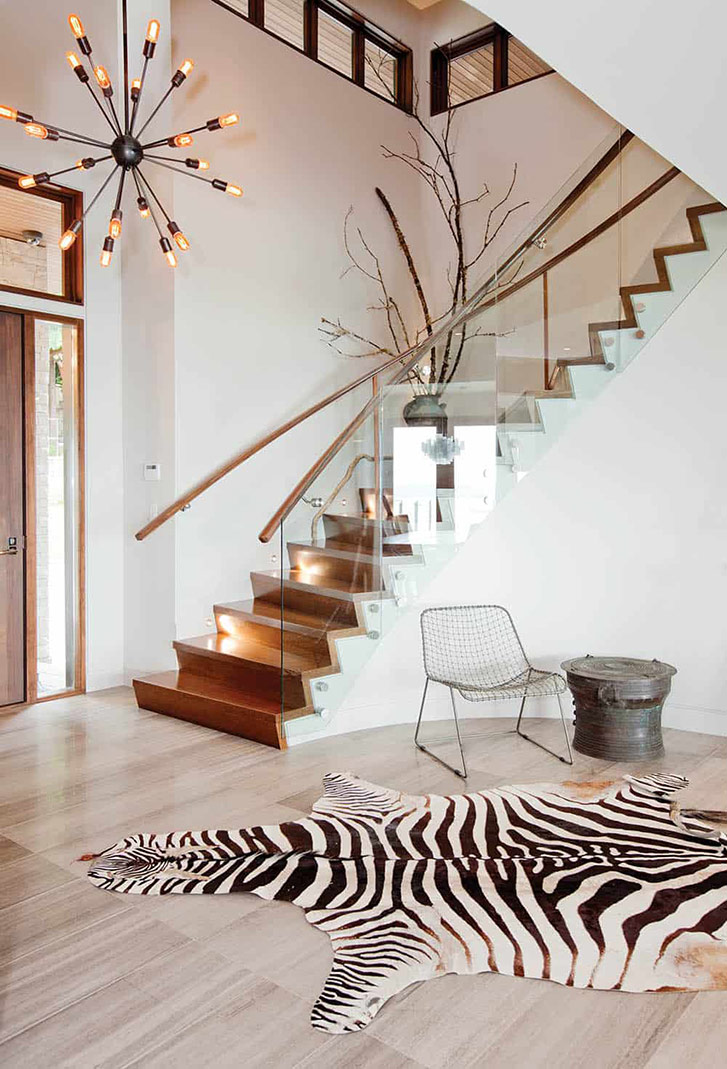 Vancouver designer Ami McKay installed a sculptural, curving staircase and a custom oversized pivoting door to take advantage of the scale of this West Coast contemporary home. “The visual weight of these key elements along with the mix of natural materials—travertine, warm woods—brings in a laid-back-luxe kind of vibe as soon as you walk in the door,” McKay explains. (Photo: Janis Nicolay.)