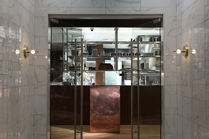 An integrated iPad fits right into the custom copper host deck at the entrance of the restaurant. "I think I’m having a moment with copper," says Greenway. "It’s wearing in and oxidizing, right behind is stainless steel shelving." 