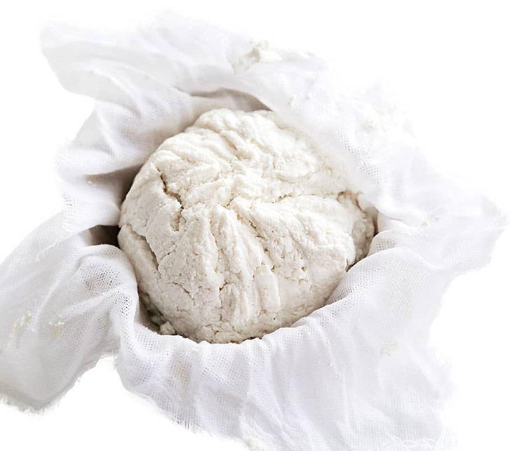 Soft homemade fresh ricotta cottage cheese made from milk, draining on muslin cloth
