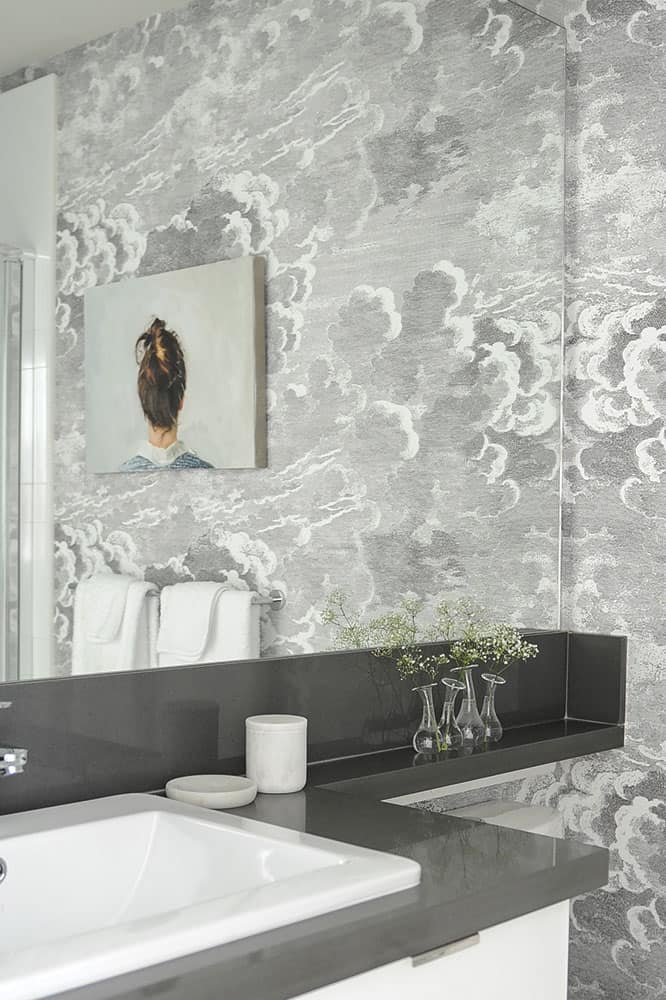 Plush white towels and original artwork decorate the guest bathroom for that high-end-hotel feel. Cloud wallpaper stays on the colour palette but adds visual interest. 