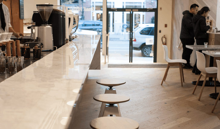 The glossy Carrara marble coffee bar extends from the front into the central area of the shop.