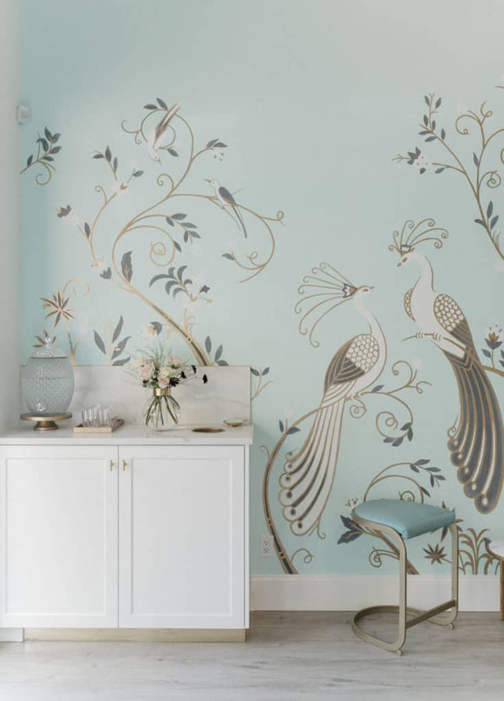 A mint-coloured wall with a mural depicting two white and gold peacocks sitting on delicately curled gold branches in La Glace ice cream parlour.