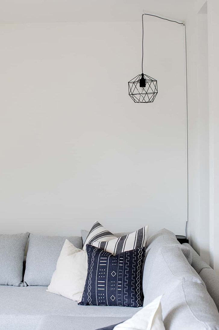 Small, geometric light hangs over sofa.