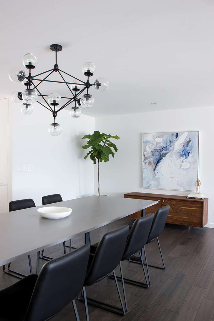 Large, geometric light hangs over long dining table.