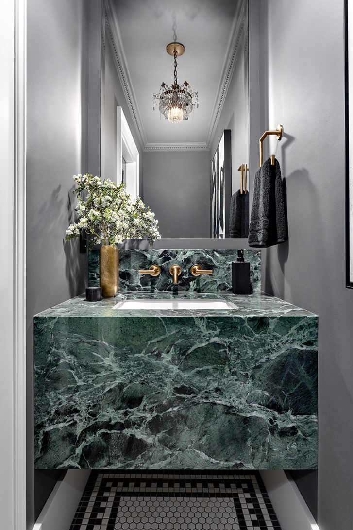 Green marble sink over black and white tile. Small bathroom.